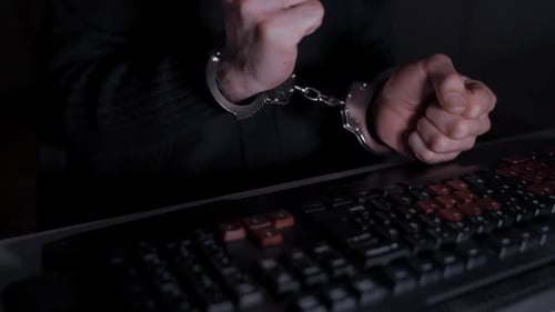 Hands Cuffed on Computer Keyboard at Night