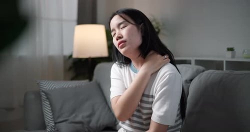 Young Woman Rubbing Sore Neck on Couch