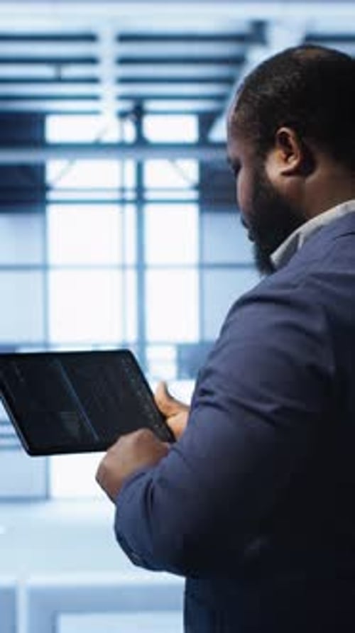 Vertical Video IT Expert in Server Hub Facility Looking for Network Bugs with Tablet
