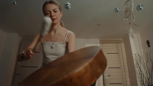 Woman Striking Metal Plate with Mallet Indoors