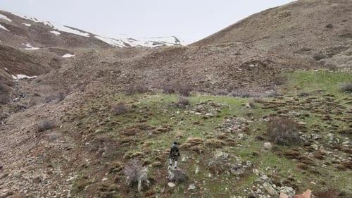 Person Standing on Rocky Hillside in Mountainous Landscape