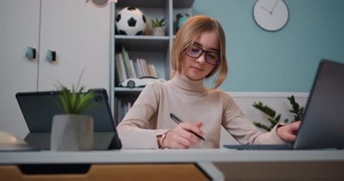 Girl Studying and Writing at Desk with Laptop