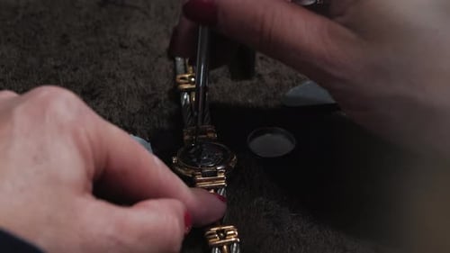 Close-up slow-motion shot of a watchmaker unscrewing screws on the back of a watch