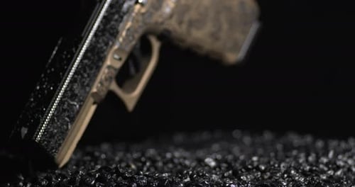 Etched Metal Version Pistol Pointed Down On Gunpowder Granules. closeup, rotating shot