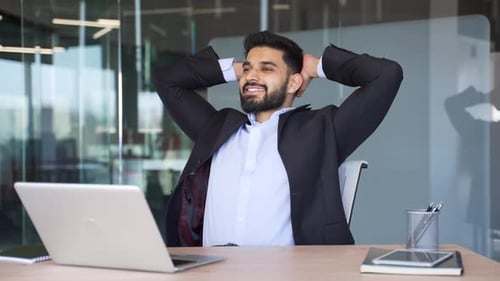 Happy businessman finished work on laptop while sitting at workplace in business office. Smiling