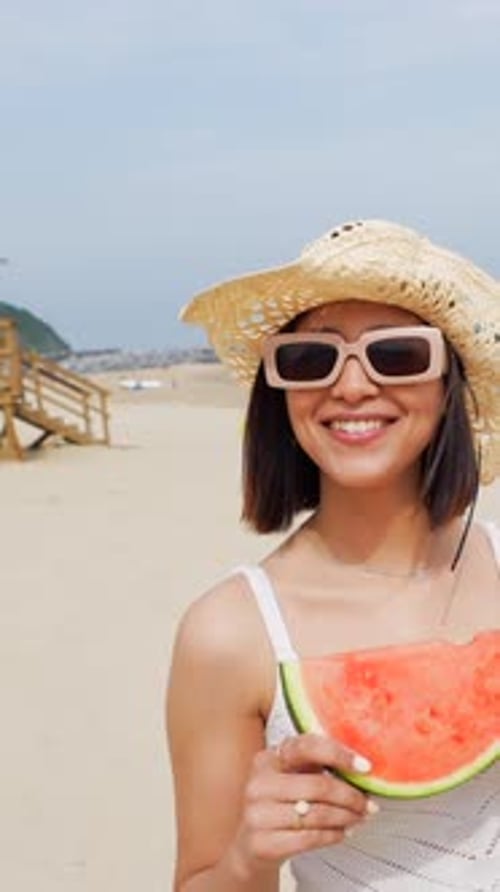 Mulher do Oriente Médio curtindo o verão na praia em férias com uma melancia