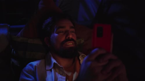 Smiling Bearded Man Using Phone While Lying Down