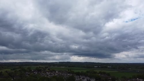 a heavy grey cloud about to start raining hard in a countryside town in the south of england
