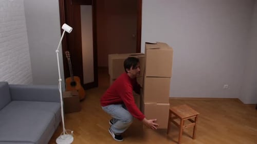 Man Lifting Stack of Boxes in Home