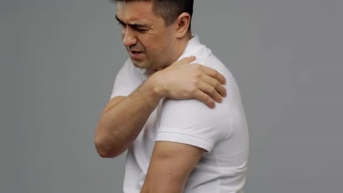 Man Experiencing Shoulder Pain on Grey Background