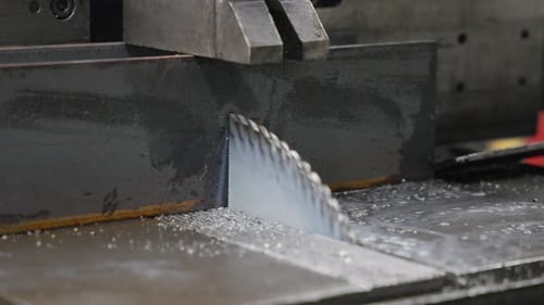 mechanized saw cutting metal beams slow motion