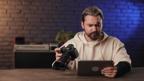 Man Using Camera and Tablet at Table