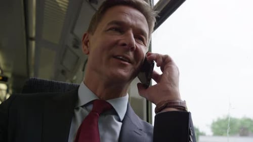 Serious Man Talking on Phone During Train Ride