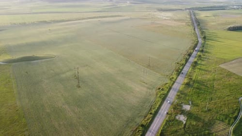 Aerial View of a Road Cutting Through a Field of Green Wheat in the Countryside