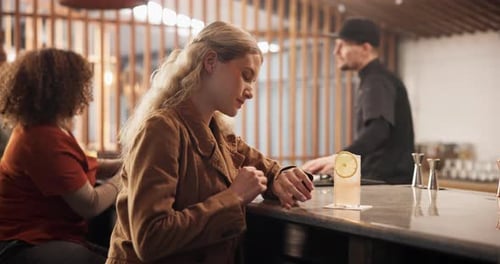 Woman, waiting and check watch at bar for date, schedule and frustrated thinking with cocktail