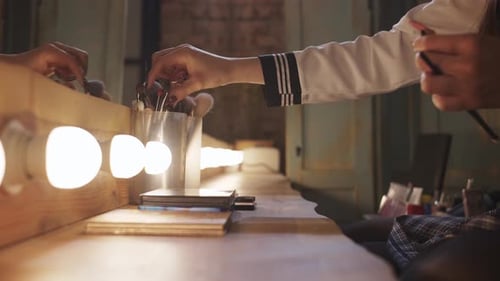 Hand Selecting Makeup Brush From Vanity