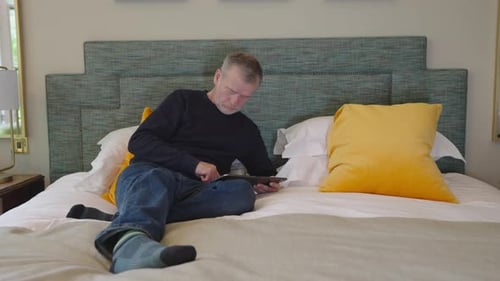 Man relaxing in bed using his tablet