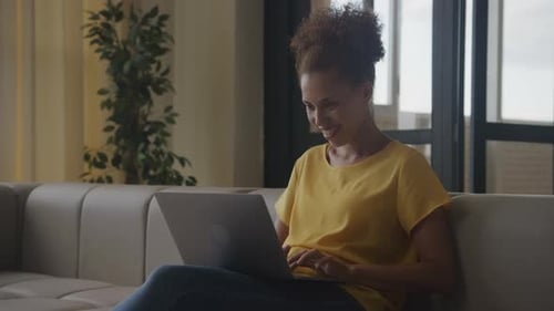 Excited Woman Using Laptop on Couch