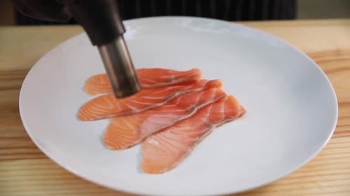 Cooking Raw Salmon with Torch on Plate