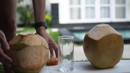 Coconut Water Pouring From Fresh Whole Coconut Into Glass