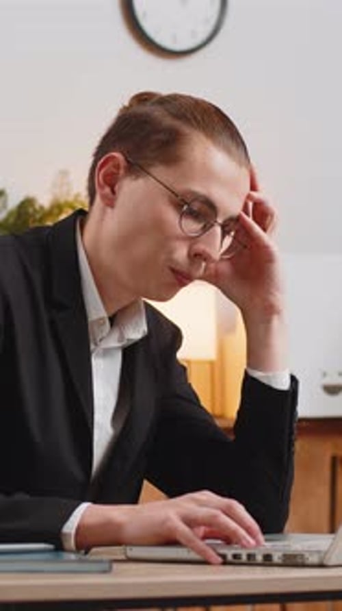 Bored Young Caucasian Businessman Guy in Formal Suit Using Laptop Computer at Home Office Desk