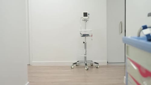 Un chariot de fournitures à roues entre à droite et se gare pour l'imagerie à proximité du moniteur vital par des panneaux radiologiques