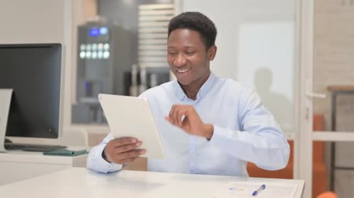 African Businessman Doing Video Chat on Tablet in Office