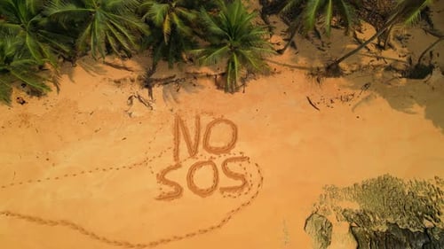 Aerial view of a desert beach with inscription in the sand saying No SOS . Descendig drone shot