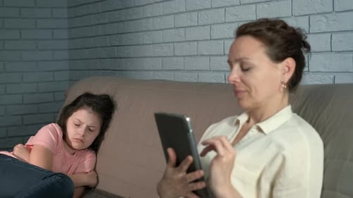Woman Using Tablet with Child on Couch