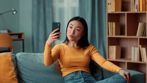 Smiling Woman Taking Selfie on Sofa at Home