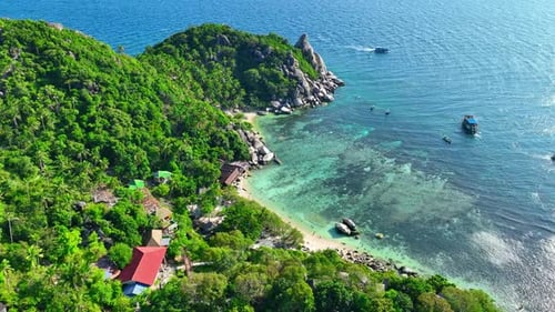 An island with green forests, rocky coasts, and turquoise waters.