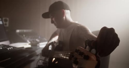 Guitarist Tuning Bass Guitar in Recording Studio