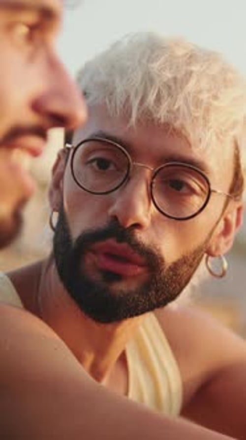 De perto, casal homossexual apaixonado passa tempo juntos sentados na praia ao nascer do sol