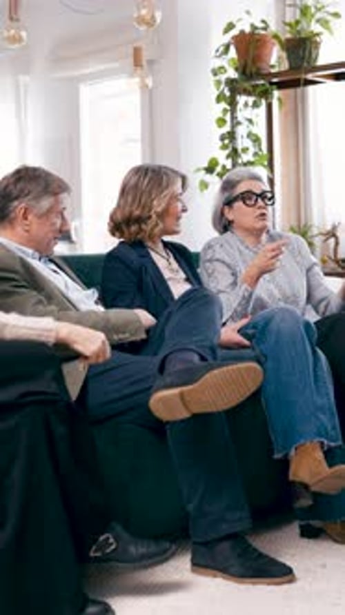 Groupe d'amis âgés parlant ensemble sur un canapé vertical