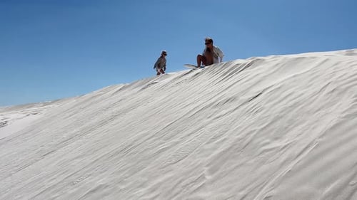 People enjoying sandboarding on desert dunes