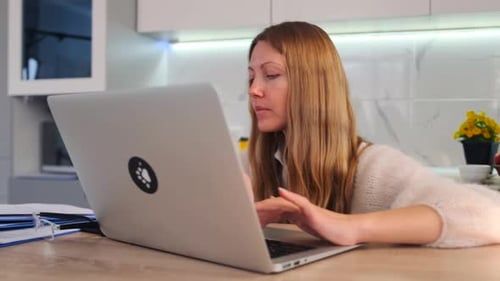 Woman Using Laptop and Talking on Mobile Phone