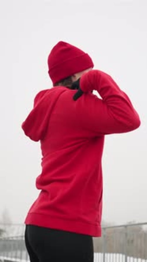 Side View of Woman Performing Hand Stretch Outdoors in Winter Fitness Routine