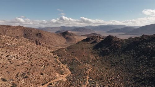 Flyover barren eroded hills in remote, hot, rocky desert terrain