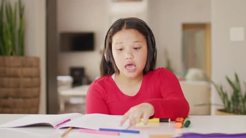 Girl Doing Homework with Headphones at Desk