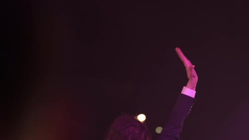Performer Raising Hand on Stage at Night