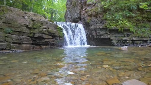 Waterfall on Mountain River with White Foamy Water Falling Down From Rocky Formation in Summer