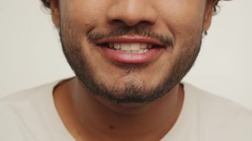 Ausgeschnittene Ansicht eines bärtigen jungen Mannes, der in die Kamera lächelt, Studioaufnahmen von einem aufgeregten Kerl, der sich ausdrückt