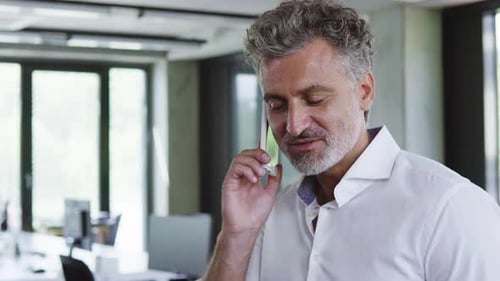 Mature businessman confidently manages his business with a phone call in the office