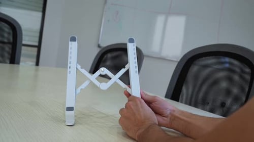 Hands Holding Foldable White Laptop Stand – Portable Workspace Accessory