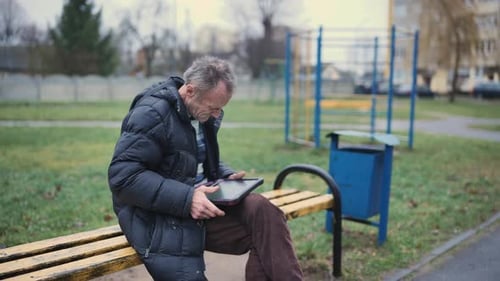 Man Enjoys Leisure Time with a Tablet in the Park Modern Relaxation Meets Technology