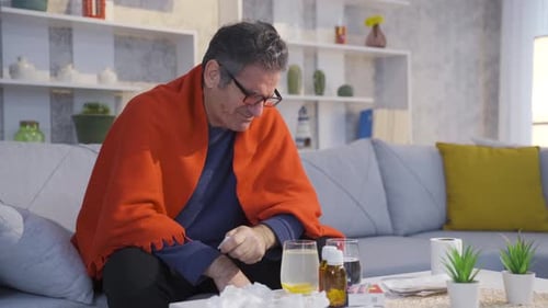 Mature man with flu runny nose, sneezing and feeling unwell at home.