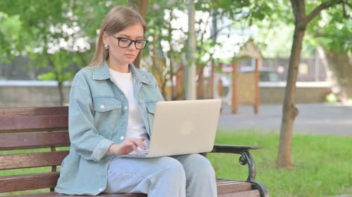 Young Woman Using Laptop on Park Bench