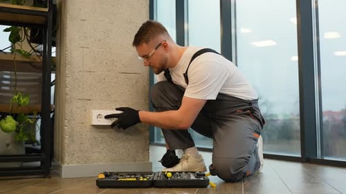 Electrician Repairing Socket Outlet in Modern Office