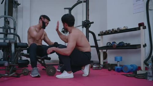LGBT couple exercising in a gym When lifting weights, they assist one another