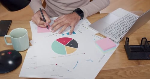 Top View on Hands of Caucasian Man Working with Charts Graphics and Figures on Desk Top View From